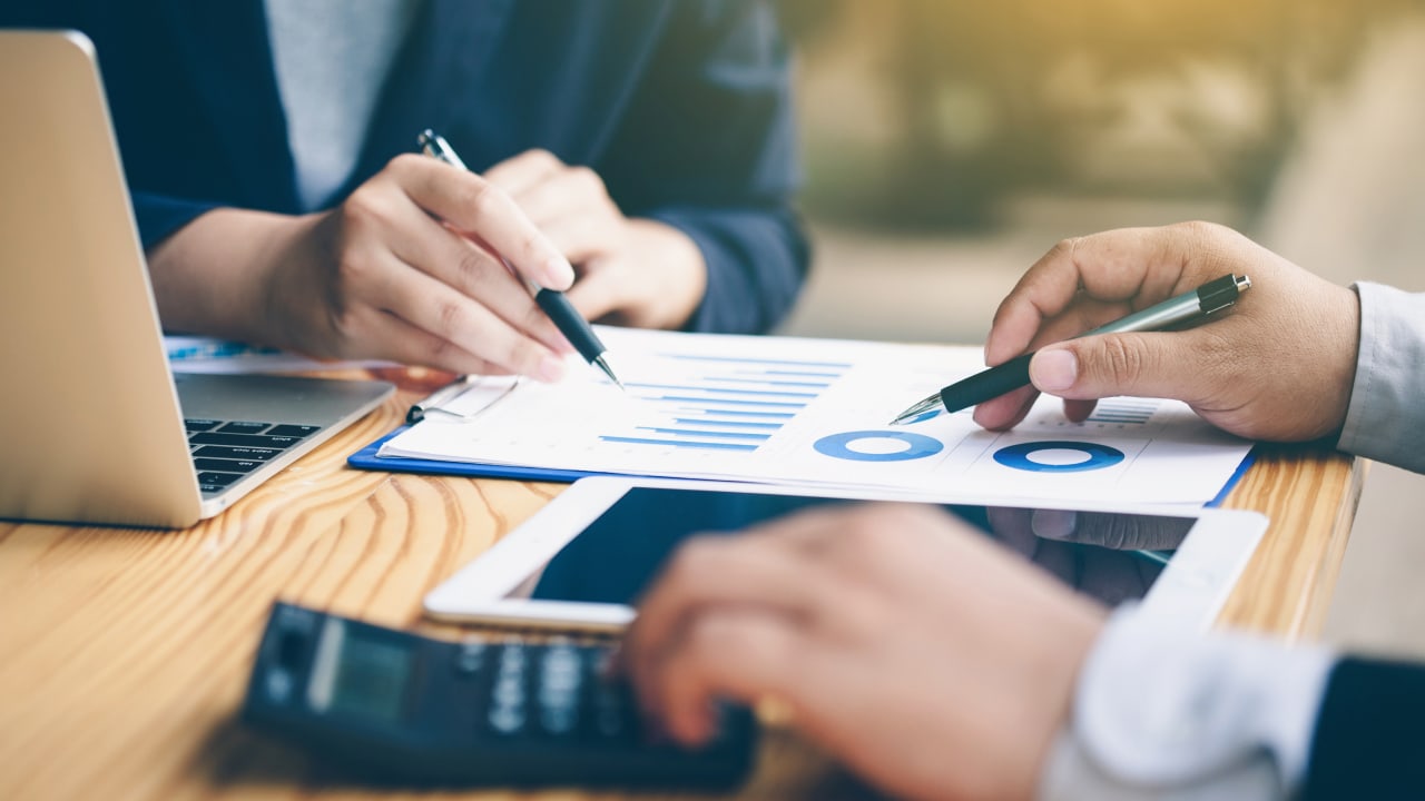 A group of professionals collaborating on a laptop, using a pen to discuss and work on business matters.